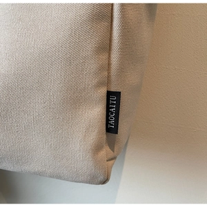 Macro shot of canvas tote bag with woven texture and black brand label details