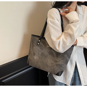 Close-up of a large vintage tote bag with textured charcoal finish and gold studs on a model