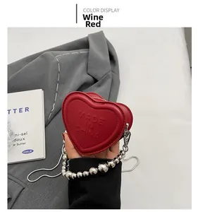 Detail of wine red heart-shaped mini bag with embossed letters and silver bead chain