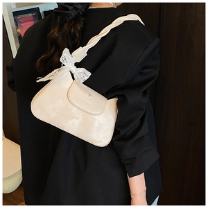 Detail of hobo bag featuring woven handle and delicate white lace bow decoration