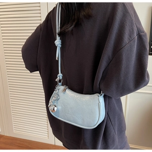 Close-up of light blue pleated faux leather crescent bag with silver ball pendant detail