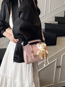 Pink leather shoulder bag with woven texture, flap closure and plush bear charm