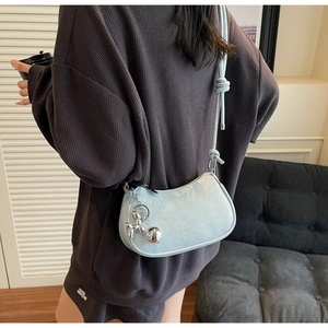 Detail of light blue pleated hobo bag with a silver balloon dog charm and zip closure