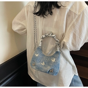 Close-up of blue denim handbag featuring silver metal butterflies and stylish chain strap