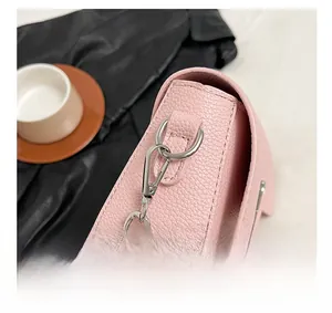 Close-up of silver metal hardware and stitching on pink lychee leather crossbody bag