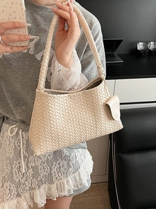 Minimalist beige woven leather shoulder bag with textured surface and thick braided strap