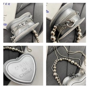 Detail of silver heart-shaped mini bag with embossed lettering and metal ball chain handle