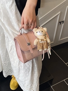 Pink vintage leather crossbody bag with cute teddy bear charm held by fashion model