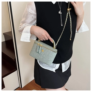 Detail of tweed quilted crossbody bag with gold flower clasp and chain strap