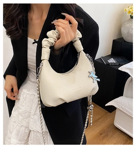 Détail du sac à main en cuir grainé blanc crème avec anse plissée et breloque cheval argentée