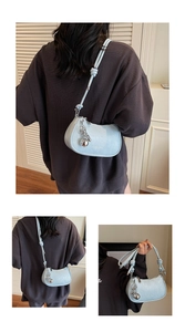 Detail of light blue crescent bag with knotted strap and silver orb chain charm