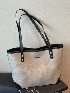 Minimalist marble texture tote bag with black trim and gold hardware on grey background