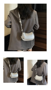 Detail of silver crescent bag with pleated texture and stylish knotted shoulder strap