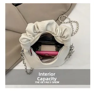 Internal capacity of white pleated cloud bag showing phone, wallet and perfume inside