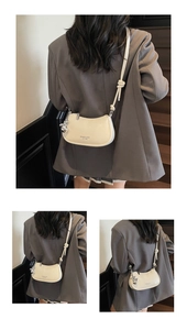 Close-up of beige half-moon crossbody bag featuring pebbled leather and silver rabbit charm