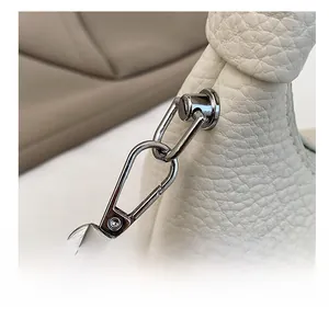 Close-up of durable silver metal hook and chain on white lychee grain leather bag