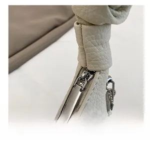 Close-up of cream lychee leather texture and smooth silver metal zipper on bag