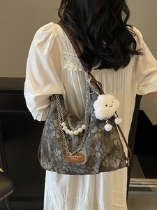 Stylish grey floral print tote bag with pearl chain and leather strap on model
