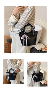Detail of glossy black bucket bag with a pink ribbon pearl pendant in a home setting