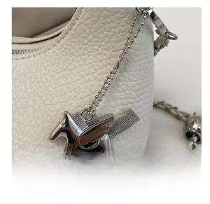 Close-up of white lychee leather bag featuring a silver Pegasus metal charm detail