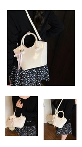 Detailed view of cream patent leather handbag with glossy finish and pink bow accessory