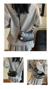 Detail shot of black crescent moon shoulder bag with silver balloon dog pendant charm