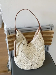Large beige hand-woven crochet shoulder bag with brown leather strap for beach vacations