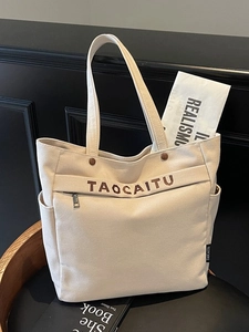 Large beige canvas tote bag with multi-pocket design on a vintage chair