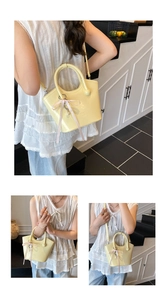 Detail of cream glossy handbag featuring a pink ribbon bow and heart pearl pendant