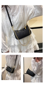 Détails de la texture florale embossée noire et chaîne dorée sur le sac à bandoulière