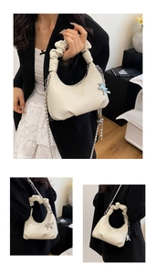 Macro view of beige lychee texture leather with pleated handle and silver horse pendant