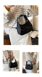 Close-up of black patent leather bucket bag with silver chain and bow detail