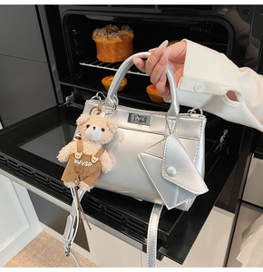 Detail of silver metallic tote bag with bear charm and mini pouch in a kitchen setting