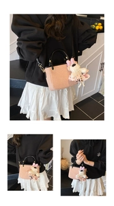 Detail of pink woven bucket bag with black leather straps and plush bear charm