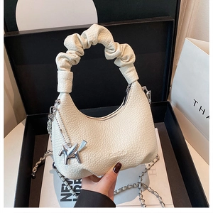 Détail du sac à main blanc en cuir grainé avec poignée plissée et breloque Pégase