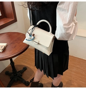 Detailed view of white soft leather tote with a cute rocking horse pendant and handle