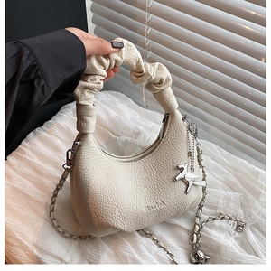 Détail du sac à main demi-lune blanc cassé en cuir grainé avec pendentif pégase