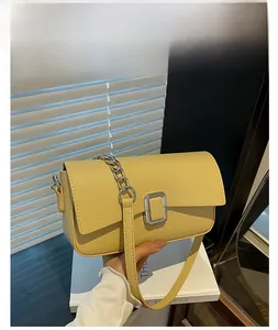 Detail of yellow lychee leather bag with rectangular silver buckle and metal chain strap