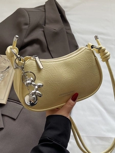 Pale yellow pleated crescent underarm bag with silver balloon dog charm and metal zipper