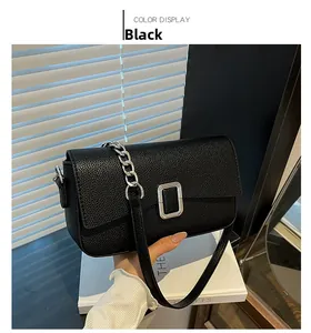 Detail of black pebbled leather handbag with silver chunky chain and metal buckle closure