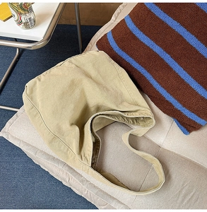 Detailed view of the large capacity khaki canvas hobo bag placed on a cozy beige sofa