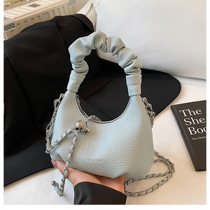 Gros plan sur le sac à main bleu clair avec poignée plissée, chaîne et bille en métal