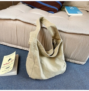 Detailed texture of large beige washed canvas hobo bag on a sofa in a home setting