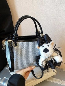 Blue and white woven handbag with black leather straps and a plush bear charm accessory