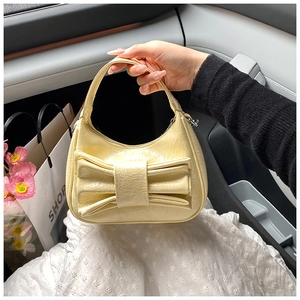 Detail of a bright yellow bucket bag featuring a large bow and glossy texture