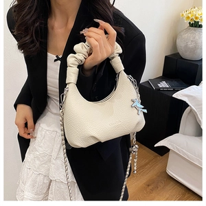 Détail du sac blanc en cuir litchi avec poignée froncée et chaîne argentée