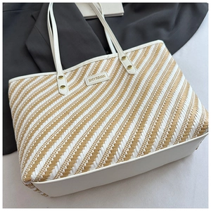 Detail of woven tote bag with stripe pattern, logo patch and gold metal rivets