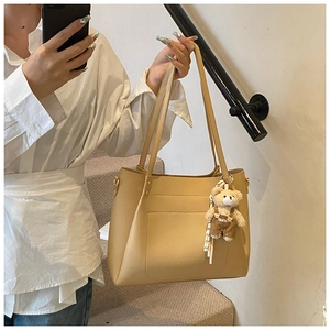 Detail of beige large tote bag with bear charm pendant and adjustable shoulder strap