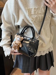 Minimalist black patent leather crossbody bag with silver twist lock and bear charm