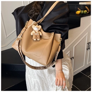 Detail of khaki tote bag with geometric patterned strap and cute bear pendant charm